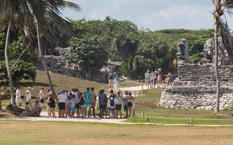 Viajeros explorando una zona arqueológica maya con guía durante un tour desde Cancún
